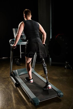Un homme avec une prothèse de jambe marche sur un tapis roulant dans une pièce faiblement éclairée, se concentrant sur sa routine d'entraînement.