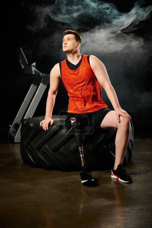 Un hombre discapacitado con una pierna protésica sentado encima de un neumático negro, mostrando fuerza y resistencia.