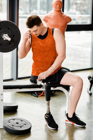 A man with a prosthetic leg sits on a gym bench, deep in thought, surrounded by the energy of the gym.