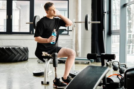 Un homme avec une prothèse de jambe s'assoit sur un banc, tenant une bouteille d'eau.