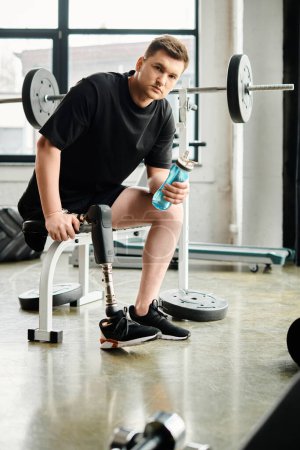 Ein Mann mit Beinprothese sitzt auf einer Bank und hält eine Flasche Wasser.