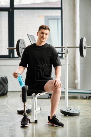 A determined man with a prosthetic leg sits in a chair, near a barbell in a gym, showcasing strength and resilience.