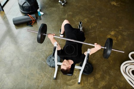 A disabled man with a prosthetic leg lies on the ground, lifting a barbell in a determined and focused manner.