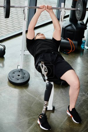 Un hombre discapacitado con una pierna protésica usando una camisa negra realiza una sentadilla en un gimnasio.