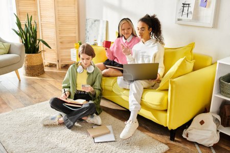 Gruppe gemischtrassiger Teenager-Mädchen, die an einem sonnigen Tag fröhlich zusammen lernen und Bücher auf einer leuchtend gelben Couch zusammenkleben.