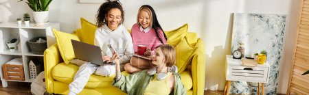 Un grupo de adolescentes interracial se sientan en una silla de color amarillo brillante, estudiando juntas en casa, fomentando la amistad y la educación.