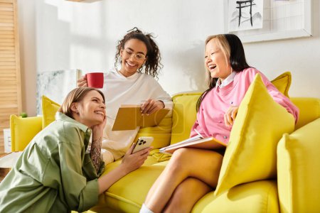 Grupo de mujeres diversas, adolescentes, vinculación en la parte superior de un sofá amarillo vibrante, estudiar juntos desde casa.