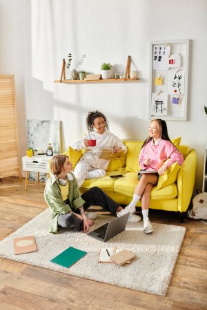 Eine bunte Gruppe von Freunden, darunter gemischtrassige Teenager-Mädchen, sitzt zusammen auf einer leuchtend gelben Couch, plaudert und studiert..