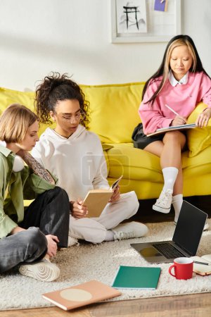 Diverse teenage girls sitting on floor near yellow couch, studying together and building friendship through shared education.