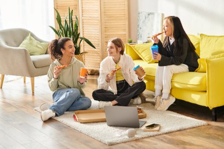 A diverse group of teenage girls enjoy each others company while sitting and chatting on a wooden floor.