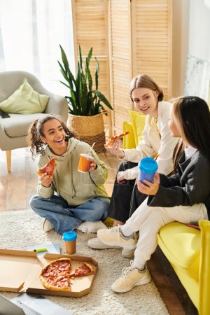 Un grupo diverso de chicas adolescentes charlando y riendo mientras están sentadas encima de un sofá amarillo brillante.
