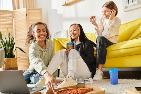 Diverse teenage girls bonding over pizza while seated on the floor in a cozy setting.