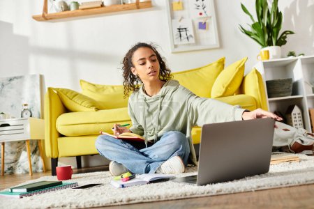 Une adolescente étudiant à la maison, profondément absorbée par l'apprentissage en ligne sur son ordinateur portable tout en étant assise sur le sol.