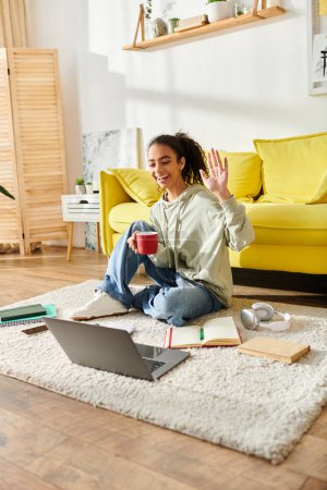 Une adolescente engagée dans l'apprentissage en ligne, étudiant avec un ordinateur portable tout en étant assise confortablement sur le sol.