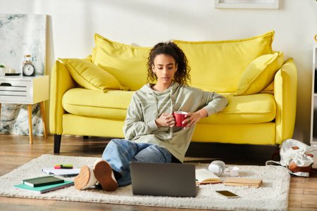 Une adolescente engagée dans l'apprentissage en ligne à la maison, assise sur le sol travaillant sur son ordinateur portable.