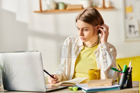Téléchargez les photos : Une adolescente concentrée est assise à un bureau, absorbée par l'apprentissage en ligne avec son ordinateur portable, entourée de matériel d'étude. - en image libre de droit