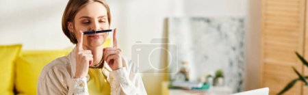 Photo for A teenage girl, studying at home, holds a pen up to her nose while e-learning with a laptop. - Royalty Free Image