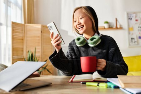 Eine junge Asiatin sitzt an einem Tisch und genießt eine Tasse Kaffee beim E-Learning auf ihrem Laptop.