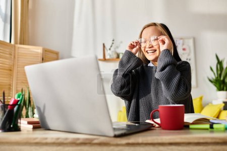 Téléchargez les photos : Une jeune fille asiatique, absorbée par le e-learning, s'assoit devant un ordinateur portable à la maison. - en image libre de droit