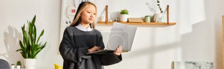 A young Asian girl immersed in digital learning, standing in a living room while holding a laptop.
