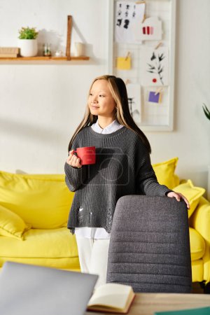 Eine junge Asiatin genießt einen friedlichen Moment in ihrem sonnenbeschienenen Wohnzimmer, in der Hand eine Tasse Kaffee.