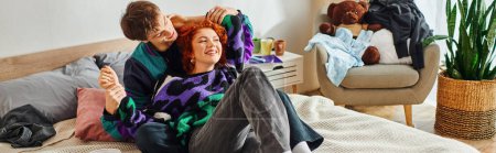 Téléchargez les photos : Jeune couple joyeux en vêtements vibrants ayant beaucoup de temps ensemble à la maison dans le lit, bannière - en image libre de droit