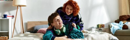 Téléchargez les photos : Séduisante femme aux cheveux rouges couchée au lit à côté de son petit ami aimant avec écouteurs à la maison, bannière - en image libre de droit