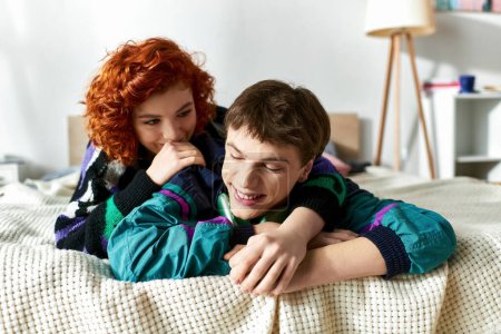 Téléchargez les photos : Belle femme joyeuse avoir du plaisir avec son petit ami joyeux avec écouteurs couchés dans le lit ensemble - en image libre de droit