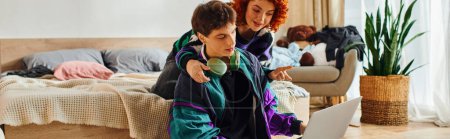 Téléchargez les photos : Séduisant couple joyeux en tenue décontractée passer du temps ensemble à l'ordinateur portable alors qu'à la maison, bannière - en image libre de droit