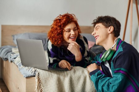 Téléchargez les photos : Belle petite amie joyeuse en tenue vibrante passer du temps à l'ordinateur portable avec son petit ami aimant - en image libre de droit