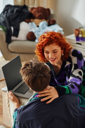 gut aussehende modische junge Paar in lässiger Kleidung verbringen Zeit zusammen am Laptop zu Hause