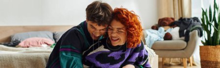 Téléchargez les photos : Séduisant couple gai et aimant dans des vêtements confortables souriant et étreignant chaudement tandis qu'à la maison, bannière - en image libre de droit