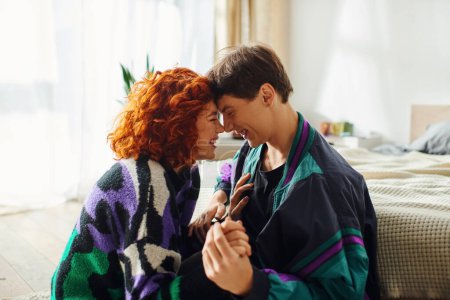 Téléchargez les photos : Attrayant couple aimant dans des vêtements à la mode en se regardant tout en s'amusant à la maison - en image libre de droit