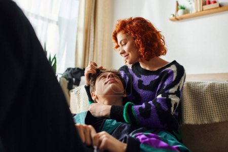 Photo for Cheerful red haired woman in casual attire hugging warmly her joyous boyfriend while at home - Royalty Free Image