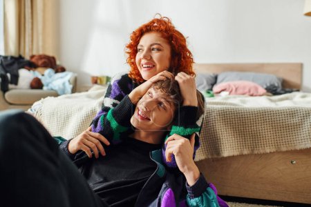red haired alluring woman in casual stylish attire hugging her loving boyfriend while at home