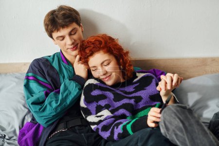 Liebendes verführerisches Paar in schicker stylischer Kleidung, das sich verführerisch im Bett umarmt und glücklich lächelt