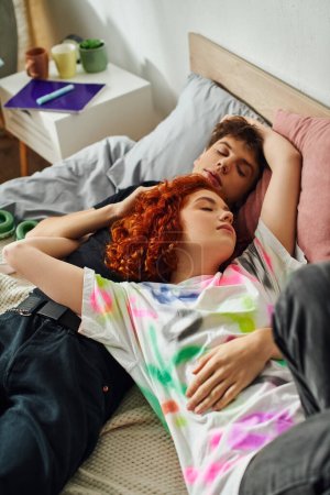 ansprechende liebende junge Paar in lebendiger Hausbekleidung entspannt zusammen in ihrem Bett, während zu Hause