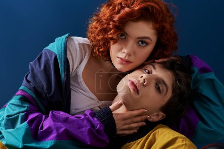 Téléchargez les photos : Jeune couple aimant dans des vêtements lumineux élégants posant sur fond blu et regardant la caméra - en image libre de droit