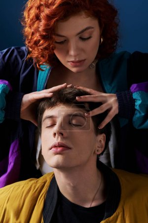 Téléchargez les photos : Beau jeune couple dans élégant vêtements vibrants câlins chaudement sur fond bleu foncé - en image libre de droit