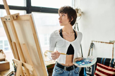Une femme tenant un pinceau et une palette.