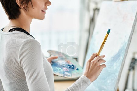 Téléchargez les photos : Une femme tient un crayon, captivée par une peinture. - en image libre de droit