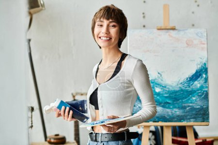 Téléchargez les photos : Femme examine la peinture tout en tenant la peinture bleue. - en image libre de droit