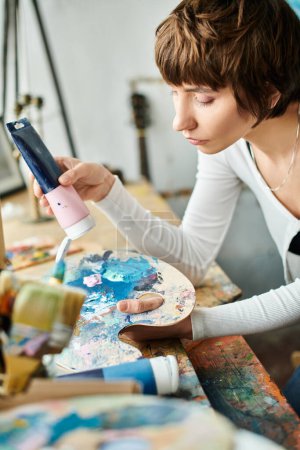 A woman meticulously paints on a canvas with a brush, creating a masterpiece.