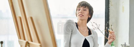 Photo for A woman standing by a window, holding a brush. - Royalty Free Image