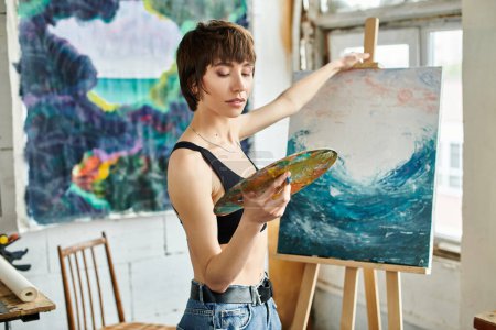 Una mujer pinta un cuadro con un pincel en la mano.