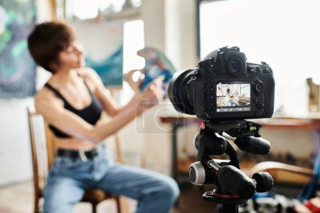 Photo for Woman sitting in chair, showing how to paint on camera. - Royalty Free Image