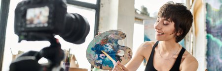 A woman in a black tank top creatively holds a paintbrush.