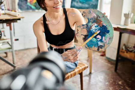 Woman seated, brush in hand, immersed in creativity.