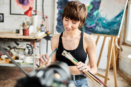 Black tank top-clad woman gracefully holds a paintbrush.