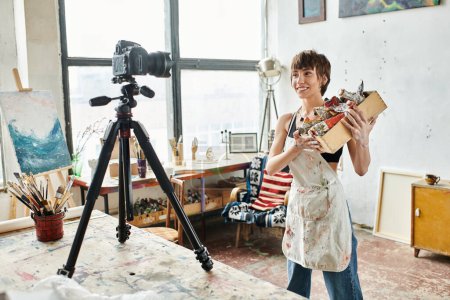 Foto de Una mujer con estilo se para, una cámara en un trípode cerca. - Imagen libre de derechos